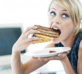 Close-up of a woman eating a large piece of cake