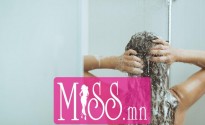 Young woman washing head with shampoo. rear view